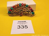 Front view of the decorative peacock hair clip showing colored stones and gold-tone metal design.