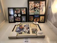 Three framed plaques displayed together on white surface including Emmitt Smith lithograph in the box.