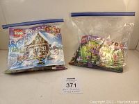 Two sealed plastic bags containing assorted Lego Friends pieces with manuals partially visible, lot tag labeled 371 in front