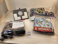 Overview of all bags and items in lot including Lego Ninjago, Hero Factory, Technic sealed bags with manuals and Lego Dimensions Game Pad black and white