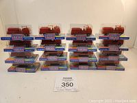 Lot of 16 Norev die cast fire engine models in clear plastic display cases with blue bases showing brand and product line.