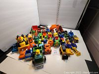 Overall group of toy trucks and construction vehicles of various colors and brands arranged on a white surface