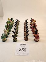 Chess set arranged in starting formation showing both sets of pieces in green/black and red/black with distinctive hand-painted details and folk style decorations.