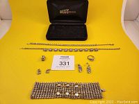 Overall lot contents including jewelry box and arranged necklaces, bracelet, earrings, brooch, and ring on yellow background