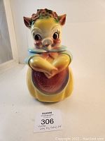 Front view of vintage lady pig cookie jar showing facial features, floral headband and pink bow at neck.