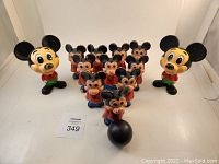 Wide view of entire set including 2 pull string talking Mickey Mouse figures on each side, 10 Mickey mouse bowling pins in formation, and black bowling ball in front.