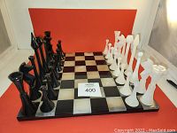 Full chess set arranged on the stone chess board with black and white pieces on opposing sides.