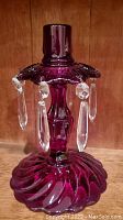 Red glass candle holder with swirled base and hanging clear crystal-like prisms