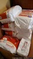 Stacked sealed packages of adult incontinence liners and diapers in orange and white packaging.
