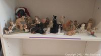 Shelf display of multiple animal figurines featuring dogs, a fairy, and birds, arranged in rows