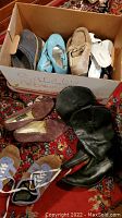 Box displaying assortment of adult and children's shoes including boots, ballet flats, slip-ons and sneakers.