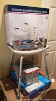 Photo showing stacked items including new boxed Premium Shower Chair with Back on top of a second shower chair and multiple boxed healthcare items underneath.