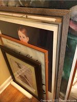 Stacked framed prints showing partial views of multiple framed artworks and rolled print at bottom