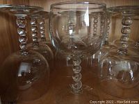 Photo showing several clear wine glasses with distinctive bubble stems arranged together.