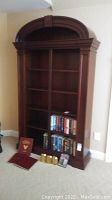 Full view of the wood bookcase with books and decorative items on lower shelves and floor in front, showing size and finish.