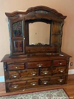 Full view of wooden dresser with mirror, cabinet door with rose glass inlay, seven drawers with brass handles, and side shelves.