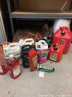 Overall view of plastic tarp, chemical containers, gas cans, and extension cords under shelf.