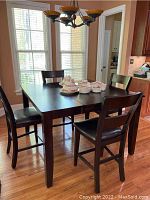 Photo showing the dark wood square high top table with four matching chairs in a kitchen/dining room setting.