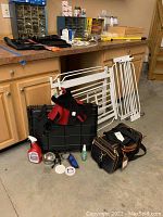 Overall lot contents including gates, vests, cage, bowl, pet care items, and bag