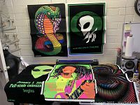 Photo showing four blacklight posters: cobra snake, alien face with text, reggae musician, and spiral vortex pattern.