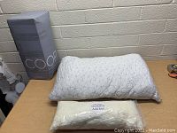 Photo of COOP Home Goods pillow with its packaging and extra fill bag on table.
