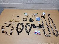 Full view of assorted jewelry pieces arranged on a table including various necklaces, bracelets, earrings, and a ring.
