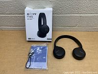 Sony WH-CH510 headphones placed on a flat surface with the original box, blue user manual sealed in plastic, and a USB charging cable visible next to the headphones.