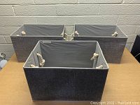 Three new StorageWorks organizer bins arranged on a table with gray fabric exterior and rope handles visible