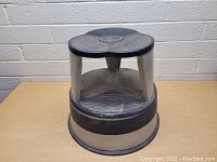 Front angle view of the vintage rolling library step stool showing the circular base and textured top step supported by three metallic triangular legs.