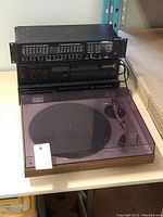 Full overview of turntable, mixer, receiver and CD player stacked on shelf