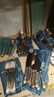 Overview of flatware arranged on blue Birks-branded cloth pouches