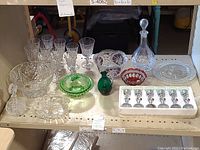 Full view of lot showing crystal stemware, green and clear glass bowls, red divided tray, decanter, and small liqueur glasses boxed set