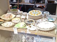 Overview of assorted dishware including devilled egg plate, plates, bowls, cups, and cream and sugar set on shelf