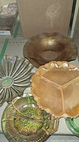 Photo showing four yellow tinted glass items including a divided dish, a fluted bowl, a flower-shaped bowl, and a dish with ridged pattern