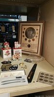 Overview of lot on shelf including framed coin display, boxed figurines, loose coins, pen set and insignia
