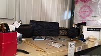 Photo showing multiple clutch purses, gold-tone perfume atomizer, jewelry pieces, and a crinoline package