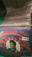 Photo showing Elvis Presley Christmas Album and row of other LPs in protective plastic sleeves inside a green storage crate.