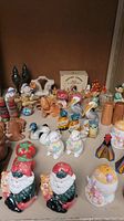 Various salt and pepper shakers featuring Santa, elves, pelicans, lobsters, pipes, and ball players arranged on a shelf.