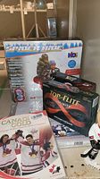 Boxed Spider Ride 64 inch inflatable snow tube, box of Top Flite Infinity golf balls, two books including Canadian Gold 2029 Olympic Winter Games Ice Hockey Champions