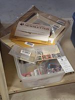 Bin with multiple sealed bags containing sports cards, pocket calendars and stamp ephemera