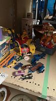 Photo showing a variety of toys including toy cars, musical boxes, and figures arranged on a table.