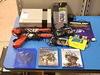 Nintendo NES console, controllers, zappers, control deck box, and game cartridges including Super Mario Bros. 3 with PS4 games Titanfall 2 and Call of Duty Cold War displayed on table