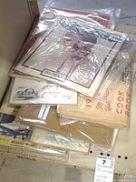 A stack of vintage magazines and ephemera, sealed in plastic, showing some titles and various paper materials of different sizes and conditions.