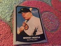 Front view of 1988 Pacific Mickey Mantle baseball card on a colorful textured rug, showing some edge wear.