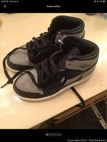 Pair of black and grey Air Jordan 1 sneakers showing left side profile, with visible wear on the ankle collar and midsole.
