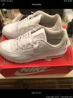 Pair of white Nike Air Max 90 sneakers on a red Nike box, side and angled top view showing overall shoe and sole condition.