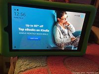 Amazon Kindle Fire 7 tablet powered on displaying Kindle ebook deals and home screen.