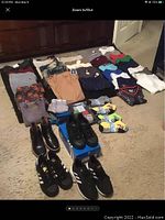 Full lot of boys clothes, socks, and shoes laid out on carpet floor