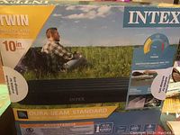 Photo of the unopened box showing the Intex twin size air bed in outdoor setting, highlighting size and brand.