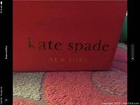 Photo of the orange-red Kate Spade box with gold embossed logo.
